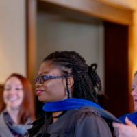 Woman draping a blue hood around a faculty member